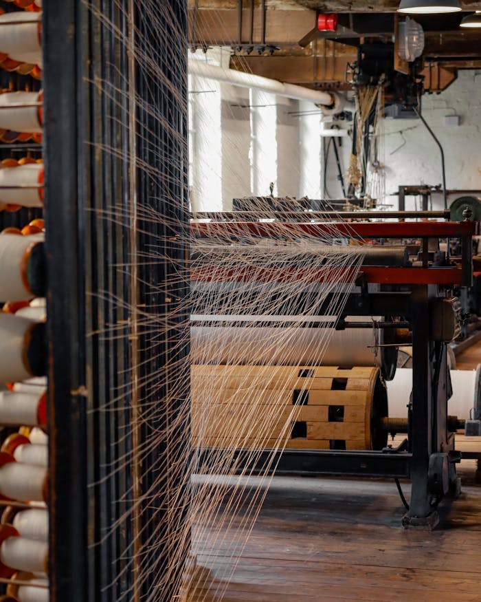 View inside a spinning mill with threads on machinery, showcasing modern textile production.